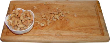 orzechy nerkowca praone z dodatkiem soli, drewniana deska do krojenia, biaa miseczka